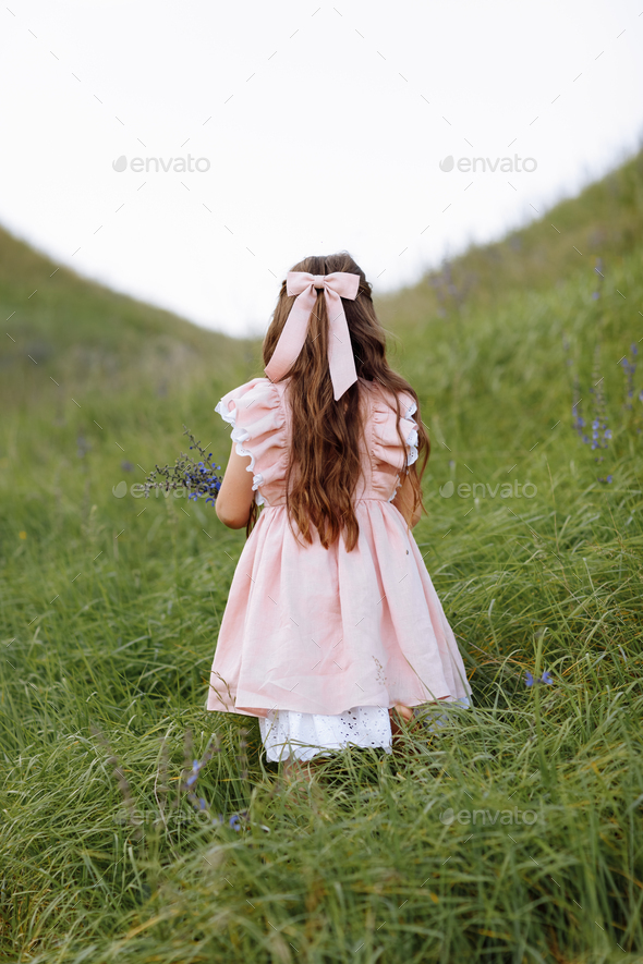 Back view of little child girl with long hair decorated silk hair bow wearing stylish pink vintage