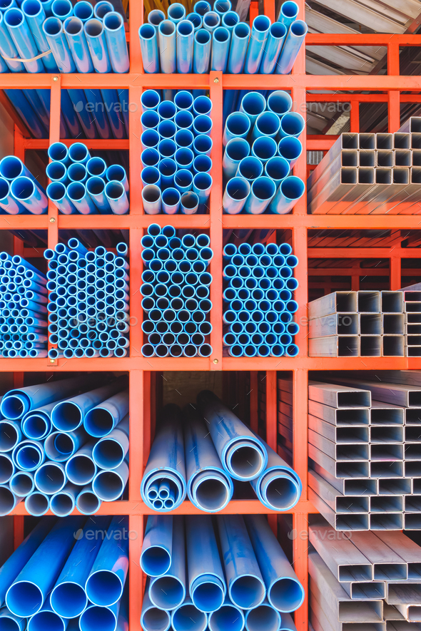 Various sizes of many blue PVC water pipes with carbon steel rectangular tubes on storage shelf
