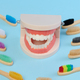 Wooden toothbrush and plastic model of dental jaw with white teeth on a blue background - PhotoDune Item for Sale