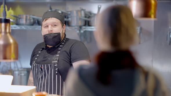 Portrait of Chubby Caucasian Chef in Apron and Cook Hat Listening Blurred Manager Scolding Employee alt