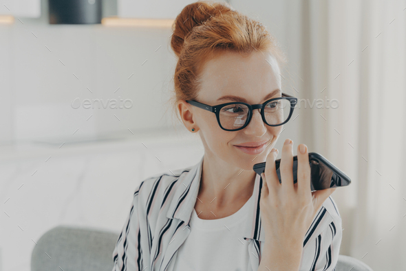 Smiling woman recording voice message on phone, communication concept