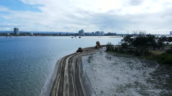 Revealing drone view of heavy machinery working on a beaching sand for a coastal erosion project. Pa alt
