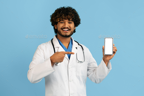 Handsome cheerful indian doctor showing smartphone with blank screen