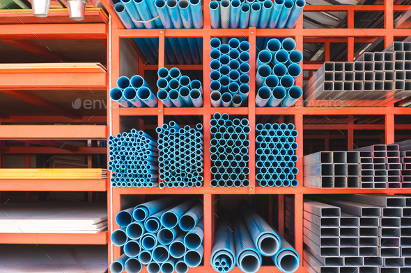 Various sizes of many PVC water pipes with carbon steel tubes and gypsum boards on storage shelf