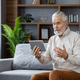 Senior gray-haired man communicates via video call from a tablet with a doctor, conducts an online - PhotoDune Item for Sale