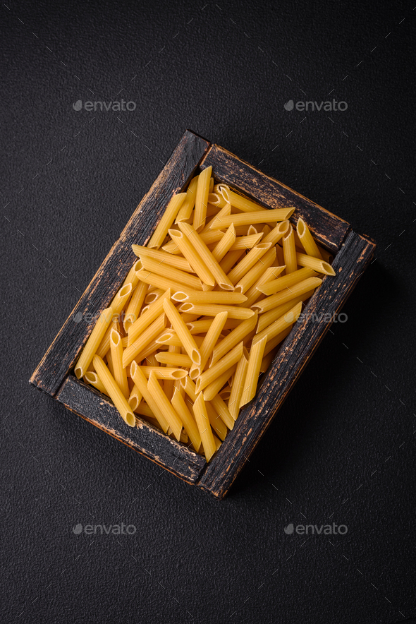 Raw penne pasta from whole grain wheat varieties with salt and spices
