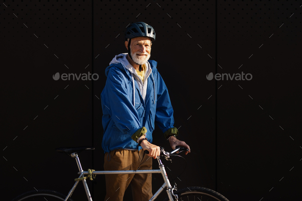Elderly man, cyclist traveling through the city by bike. Vital senior city commuter riding a bike