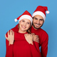 Cheerful Couple Wearing Red Sweaters And Santa Hats Posing On Blue Background - PhotoDune Item for Sale