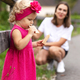A two-year-old girl in a pink dress tries cookies on a walk - PhotoDune Item for Sale