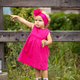 A little girl in a pink dress with a cookie in her hands points to something with a serious face - PhotoDune Item for Sale