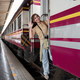 Young woman carrying a backpack waits for a train at the train station while travel on a weekend - PhotoDune Item for Sale