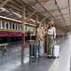 Young woman holding a suitcase waiting for a train at the train station while traveling on a weekend - PhotoDune Item for Sale