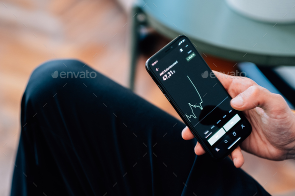 Man using his smartphone to check the crypto-trading platform