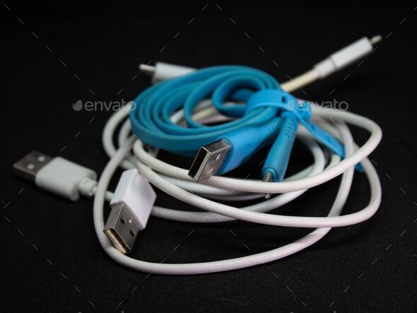 Messy pile of USB charging cable on isolated black background