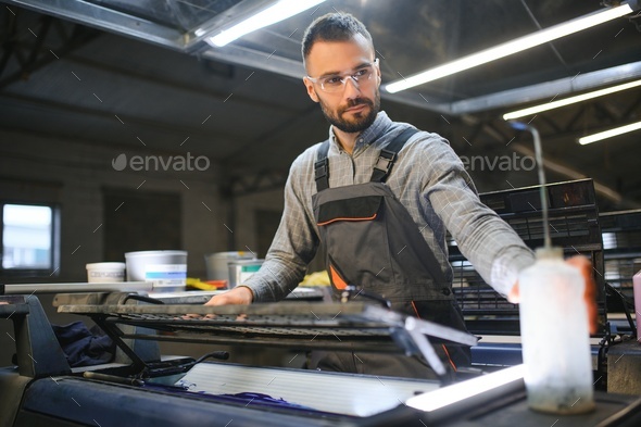 Print worker trying to fix the problem on computer to plate machine in printing shop