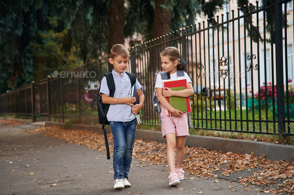 Holding Notebook And Books. Young School Children Of Boy And Girl Are 