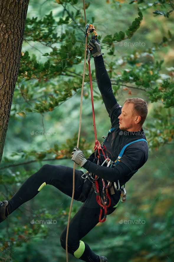 Side view, using the rope, hanging. Man is doing climbing in the