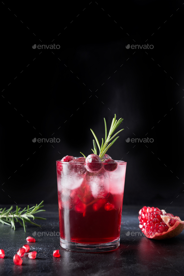 Pomegranate Christmas cocktail with rosemary, champagne, club soda on grey concrete table.
