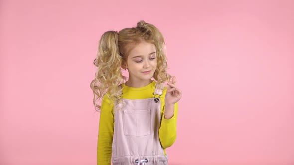Cute Female Child Is Winding Her Hair on the Finger. Slow Motion alt
