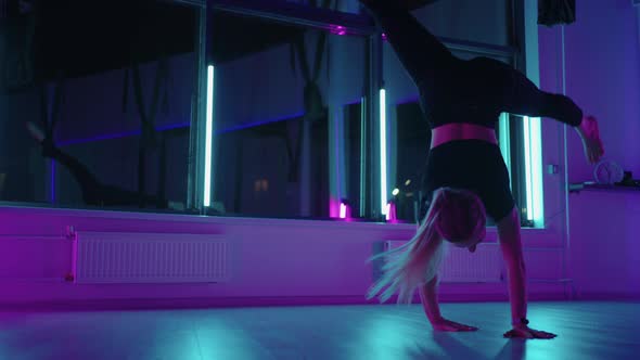 A Woman Dances in a Studio with a Neon Light Performing Graceful Exercises and Movements From alt