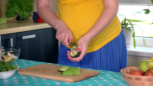 Pregnant House Wife Belly and Hands Peeling Off Avocado Fruit in Kitchen at Home