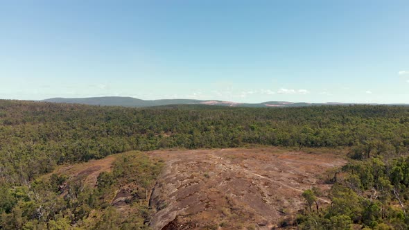 Aerial drone shot towards hikers in a clearing surrounded by green bushland alt