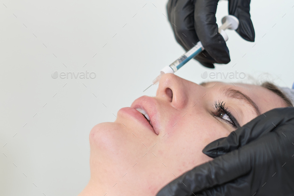 A cosmetologist carefully injects a client's lips. Enhancements come with both benefits and risks.