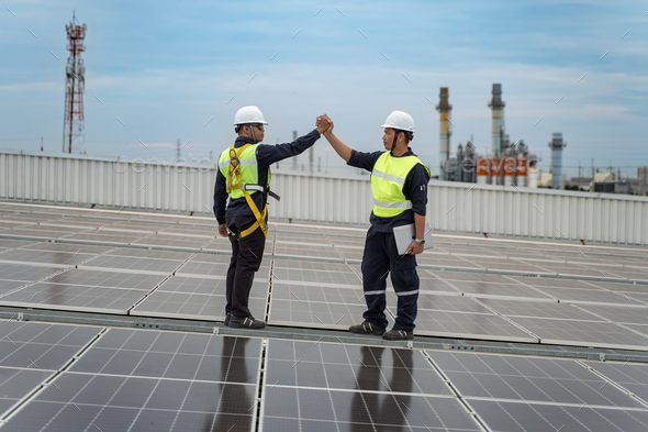Engineers give a high five with solar panel on roof of the factory, Concept of installed solar panel