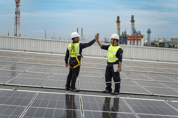 Engineers give a high five with solar panel on roof of the factory, Concept of installed solar panel