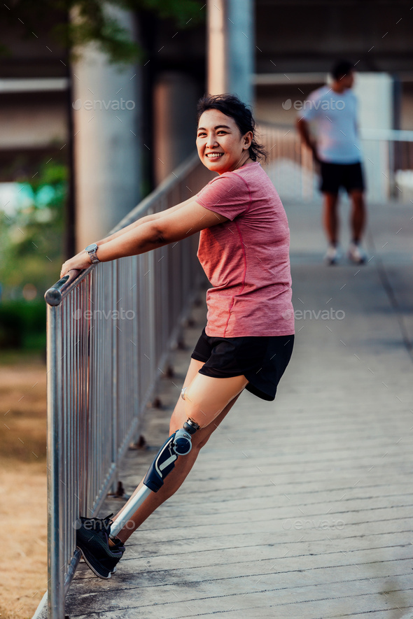 Athlete with prosthetic leg doing warm up exercise on park. Stock Photo ...