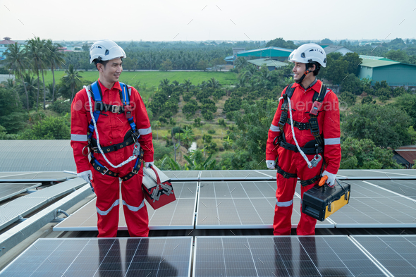 Engineers and technicians wearing full harnesses and helmets Solar panels, survey the job site