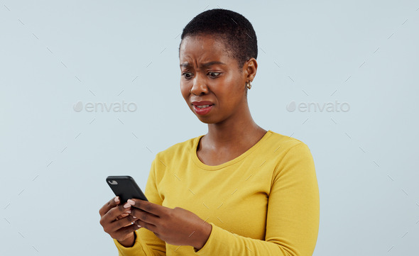 Frustrated black woman, phone and shocking news on social media, terrifying or bad against a studio