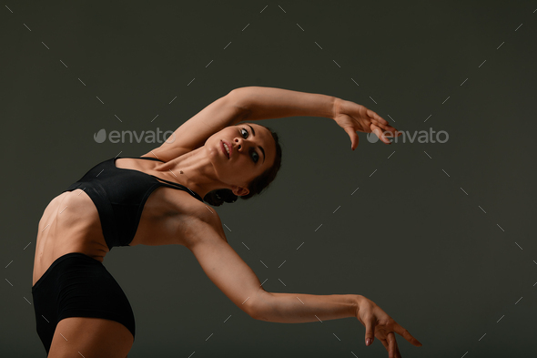 Beautiful female ballet dancer on a grey background. Ballerina is