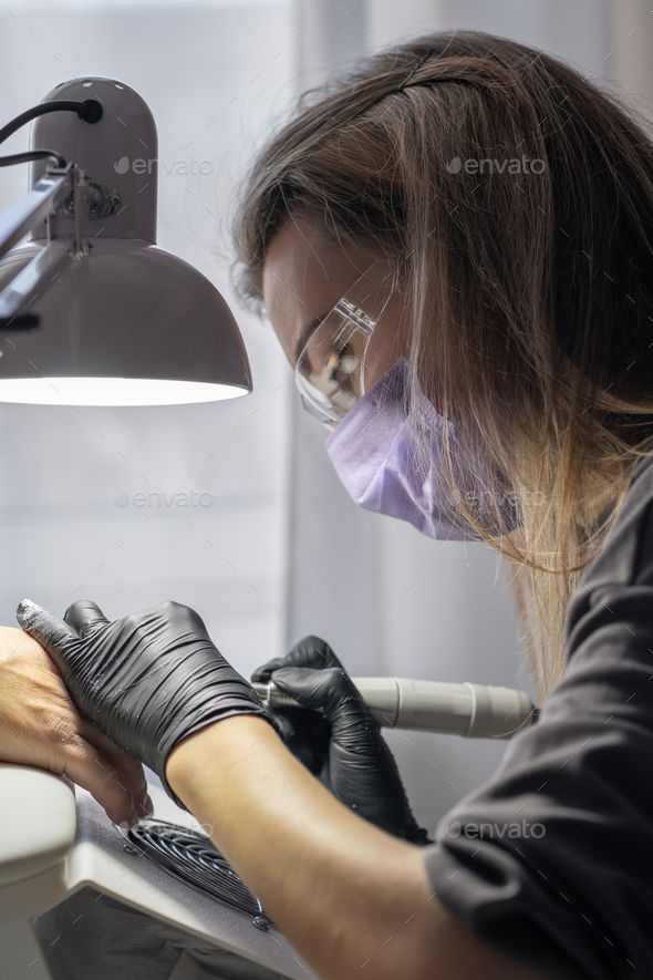 Manicurist at work. Professional manicurist removes worn nail design
