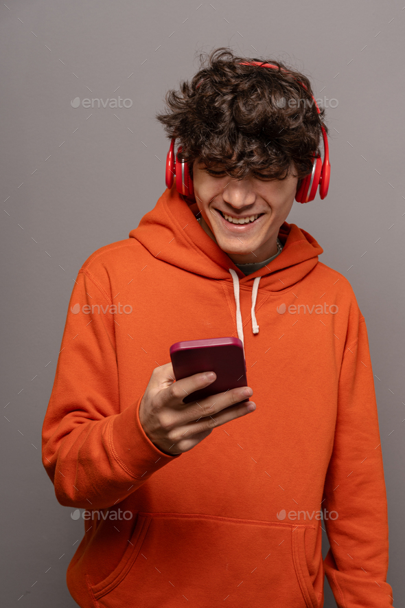 Happy Youngster Listening to Music and Using Smartphone.
