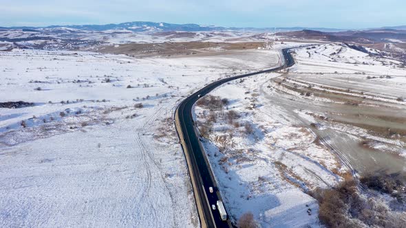 Aerial View of a Winding Road With Passing Cars in a Frosty Winter Sunny Day alt