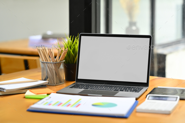 Office desk with laptop, financial chart, calculator and pencil holder ...