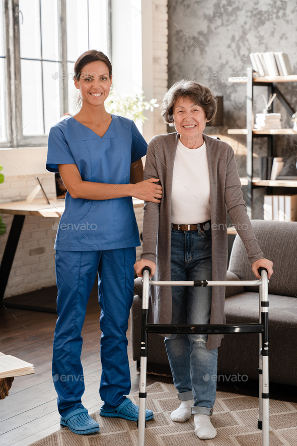 Smiling elderly patient and medical worker with walking frame having rehabilitation after injury