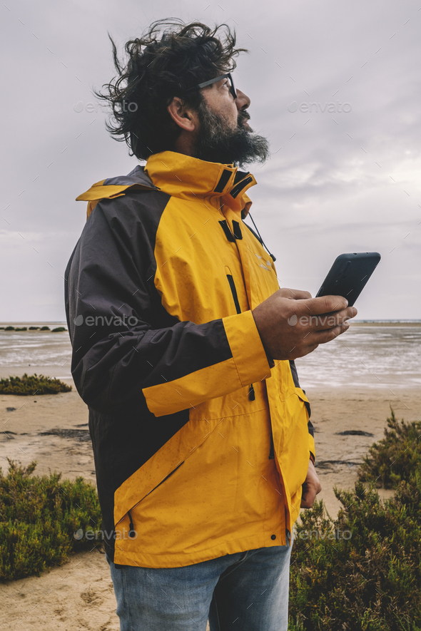 One man standing in the wind in outdoor leisure activity alone using mobile phone and roaming