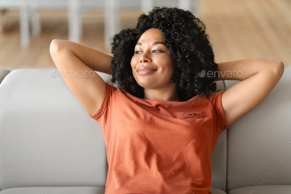 Portrait Of Calm Beautiful Black Female Leaning Back On Comfortable Couch
