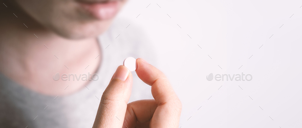 People taking or holding a white medicine pill in hand