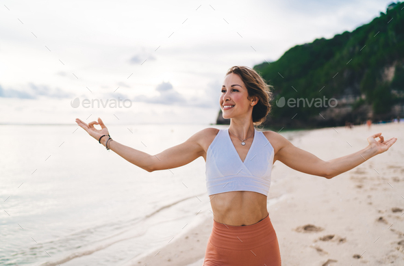Happy woman doing yoga in revolved pose on beach