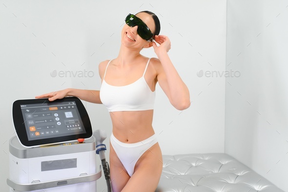 Young beautiful woman with laser hair removal machine in cosmetology cabinet