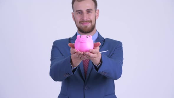 Happy Bearded Businessman Giving Piggy Bank