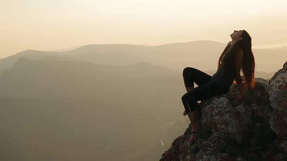 A young woman sitting on top of a mountain