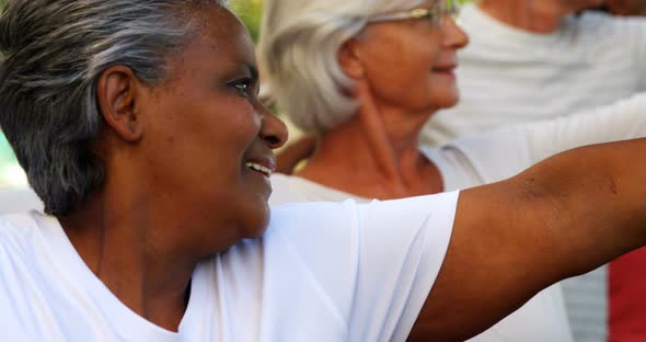 Senior friends doing stretching exercise in garden 4k alt