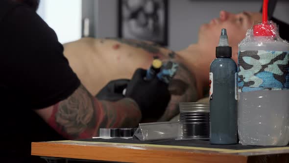 Tattoo Artist Working at His Studio, Doing a Tattoo on Chest of His Client alt