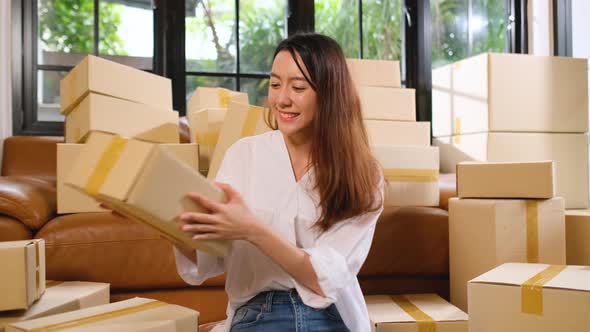 Young Asian woman receive throwing boxes and sit among many boxes then action of happy alt