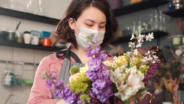 Young Woman Florist Is Holding Bouquet of Flowers Standing in Interior During Pandemic.