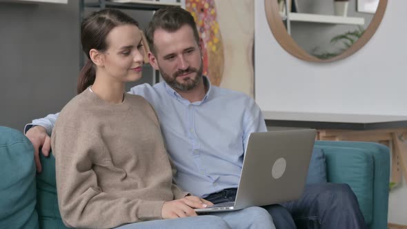 Couple Working on Laptop Together While Sitting on Sofa alt